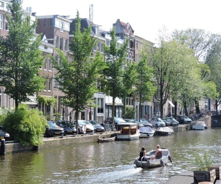 Zwei Personen fahren mit einem Boot auf einer Gracht in Amsterdam.