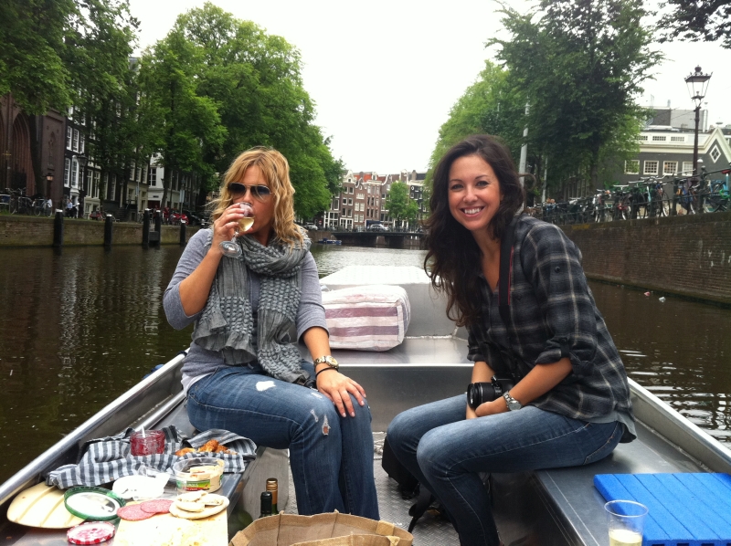 Zwei Frauen mit Snacks und Getränken auf einem Schaluppenboot auf den Amsterdamer Grachten.