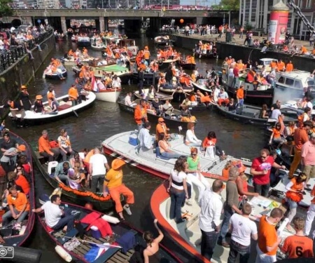 Verschillende bootjes op de grachten van Amsterdam tijdens Koningsdag.